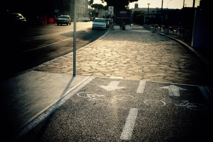 Ein markierter Radweg neben Kopfsteinpflaster, im Asphalt Fahrradpiktogramme und Richtungspfeile