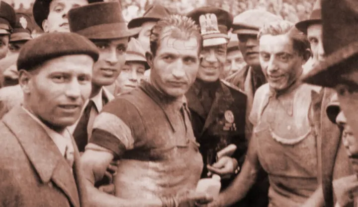Historische Aufnahme: Fausto Coppi und Gino Bartali im Trikot inmitten einer Menschenmenge
