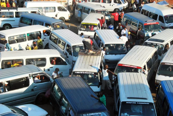 Dicht gedrängte Kleinbusse und Autos in einem Stau, dazwischen Menschen zu Fuß