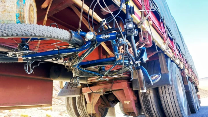 Ein blaues Reiserad ist unter dem Anhänger eines Lastwagens festgezurrt