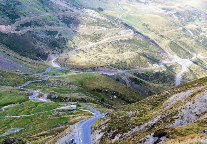 Blick von oben auf die Serpentinen der Tourmalet-Ostrampe durch grüne Bergwiesen