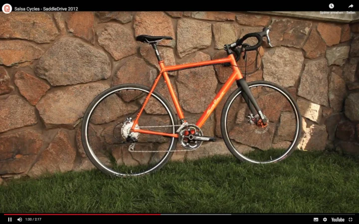 Bildschirmfoto eines Videos von Salsa Cycles aus 2012: ein orangefarbenes Warpig an einer Steinmauer