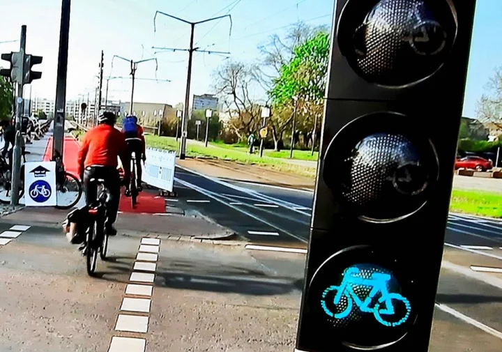 Zwei Radfahrende auf einem Radweg, daneben eine Fahrradampel mit leuchtendem Radsymbol