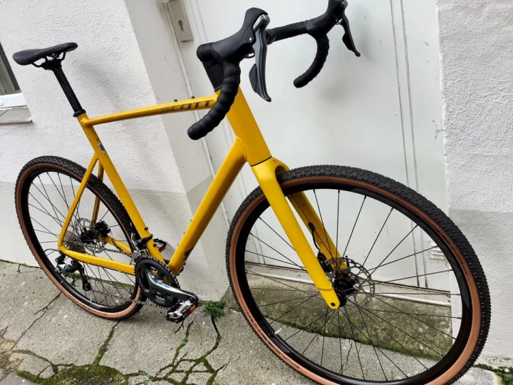 Das Scott Speedster Gravel 40 EQ in Senfgelb von der linken Seite an einer weißen Wand