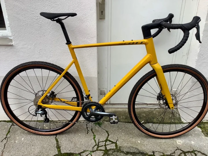 Das Scott Speedster Gravel 40 EQ in Senfgelb schräg von vorn, mit stolliger Bereifung