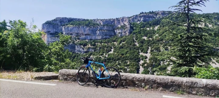 Ein Rennrad lehnt an einer Mauer über einer Schlucht, dahinter helle Felswände
