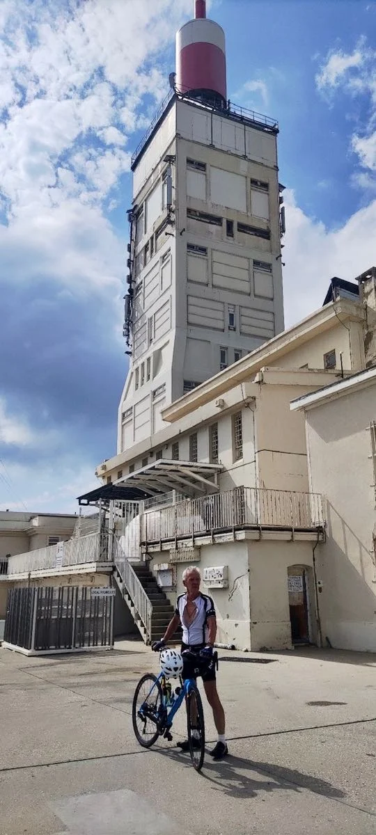 Ein Radfahrer steht mit seinem Rad vor dem Wetterturm auf dem Gipfel des Mont Ventoux