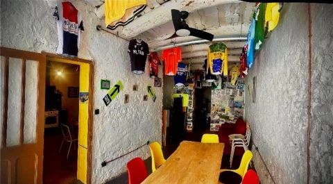 Der Innenraum eines Radsportcafés, an Wänden und Decke hängen bunte Trikots