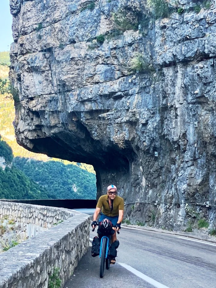 Ein Radfahrer kommt aus einem in den Fels gehauenen Tunnel auf einer Bergstraße