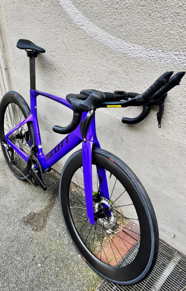 Das violette Scott Foil RC 10 mit Triathlonaufsatz am Lenker, an einer Wand stehend