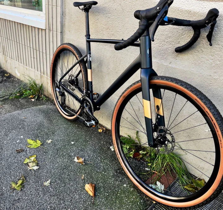 Das Scott Speedster Gravel 20 in Schwarz lehnt an einer Wand, Reifen mit hellen Flanken