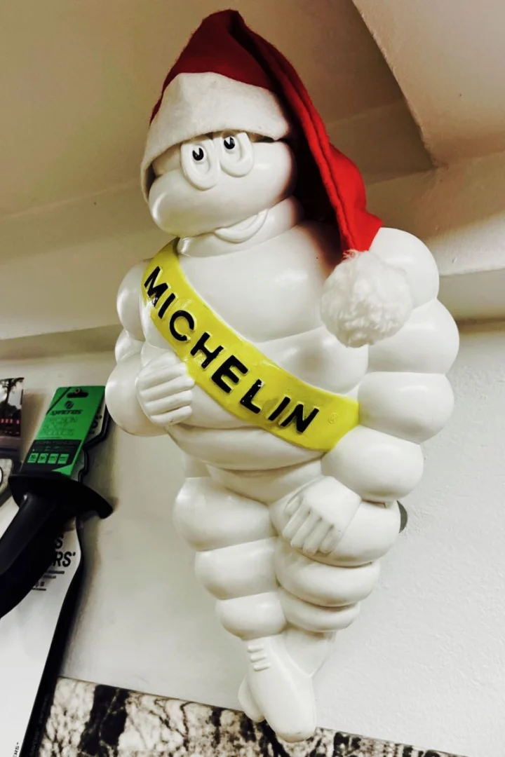 Eine Michelin-Männchen-Figur mit Weihnachtsmütze steht auf einem Regal im Laden