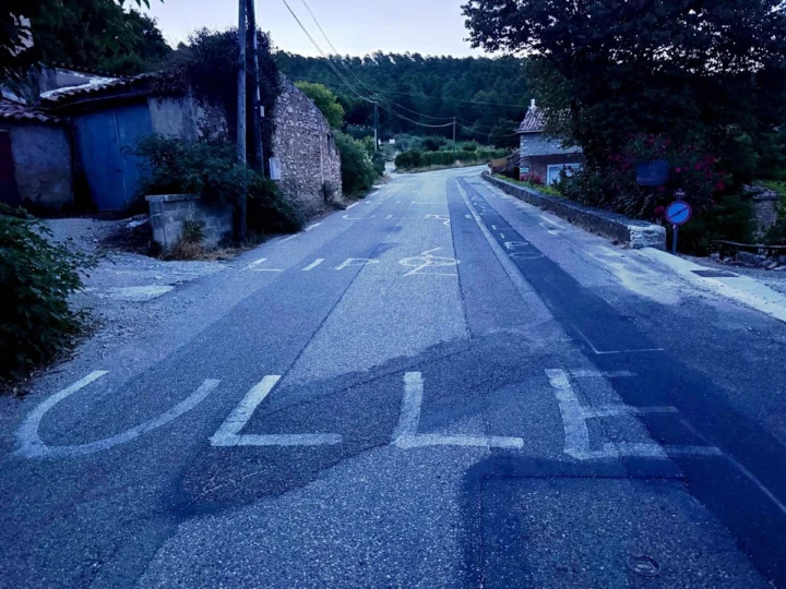 Auf den Asphalt gemalter Schriftzug „ULLE“ auf einer Dorfstraße in der Morgendämmerung